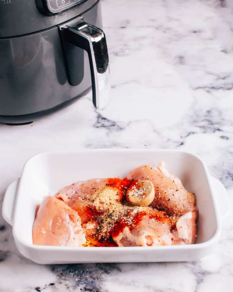 Preparing Air Fryer Boneless Chicken by adding seasoning